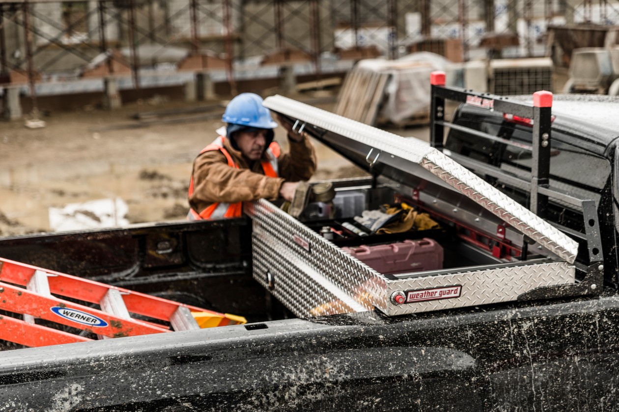 A worker opening a toolbox in the back of a truck