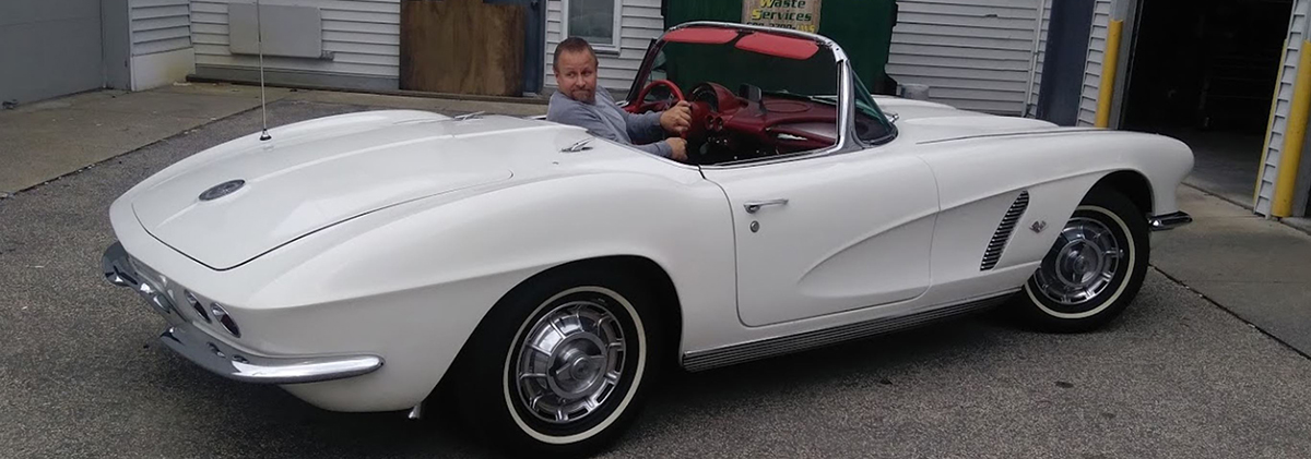 Man backing up a white Corvette